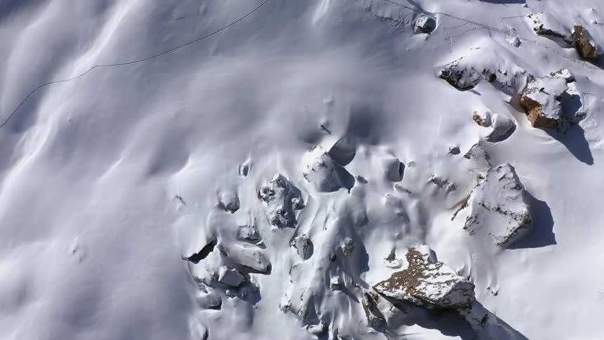 A thick blanket of snow covers the side of a mountain