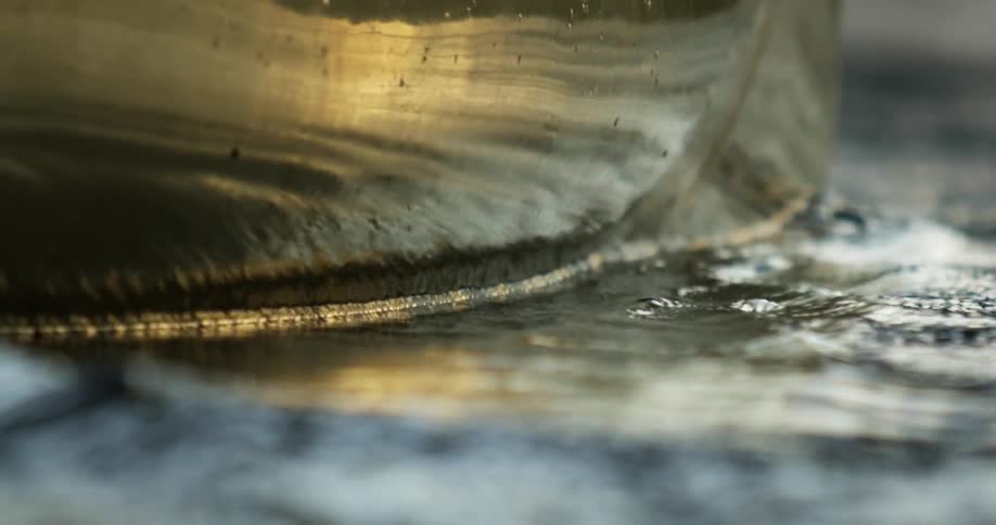 Shiny canoe side flows through reflective water as paddle cuts across surface