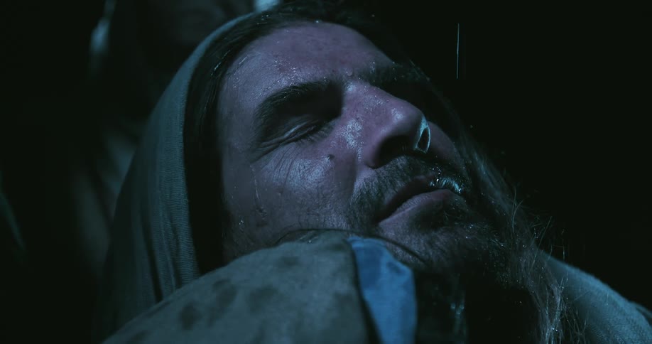 The rain is pouring on a man at night