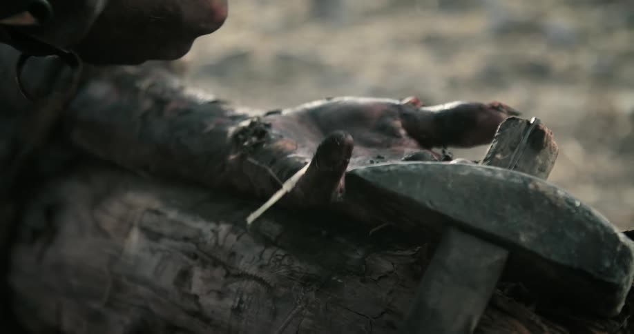 A person is being tied to a wooden stake with rope