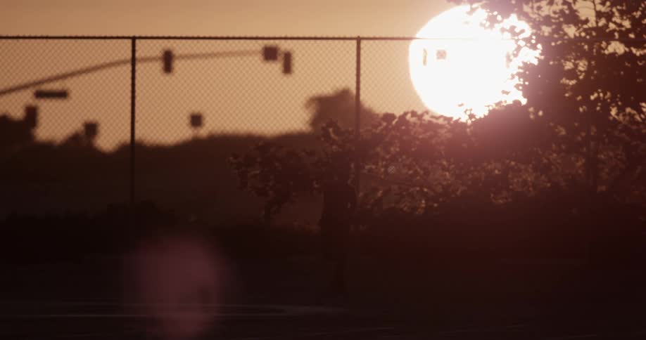 A person is traveling by the fence at sunset