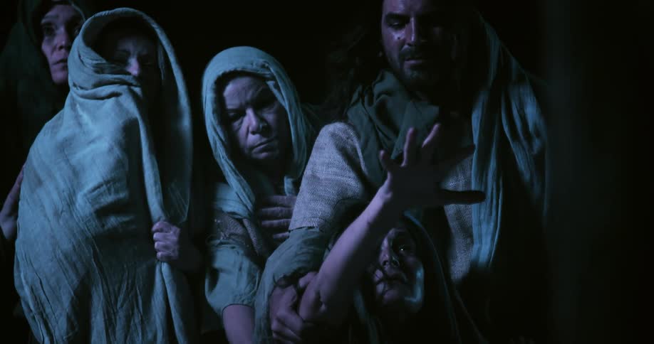 A man holds a woman as she reaches up pleading