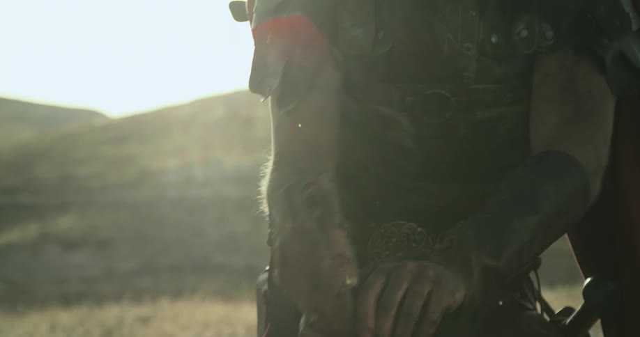 A gladiator walks over and ties a person to a log
