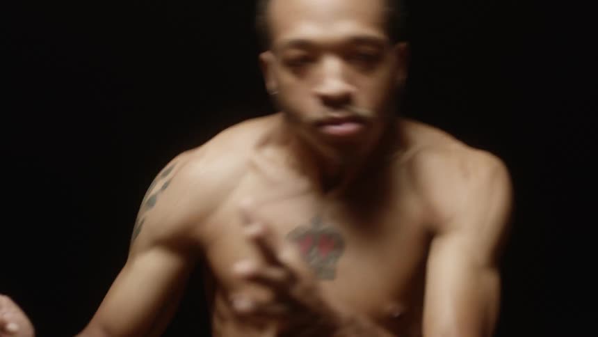 Man moves through dance poses in dark studio under lights