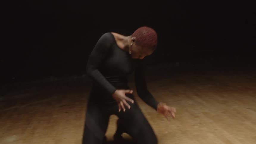 A woman in a room on the floor dancing with a black background