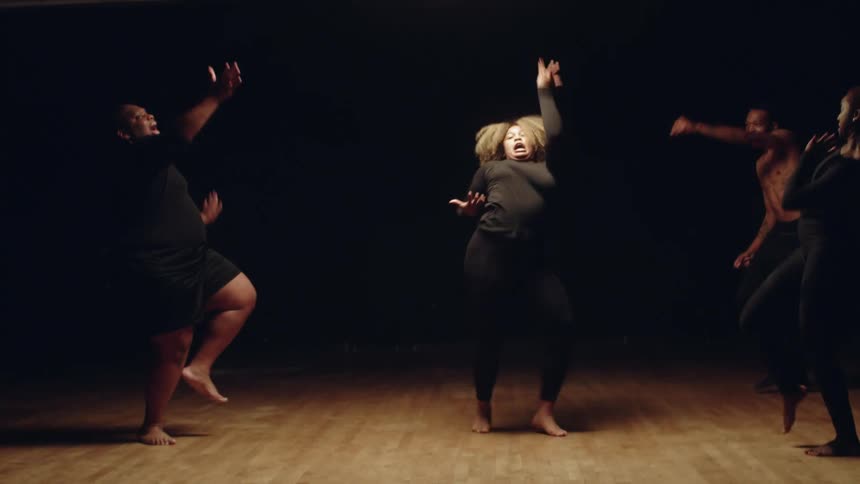 A woman does a hip hop style modern dance as her friends dance in a semi circle around her