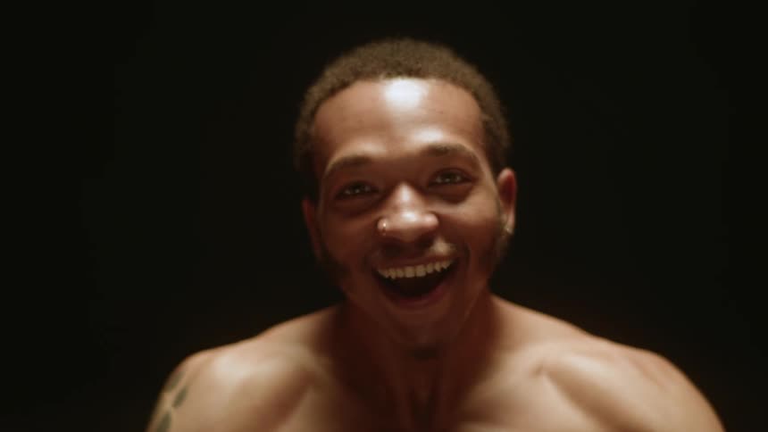 Man smiles and gestures then dances a little