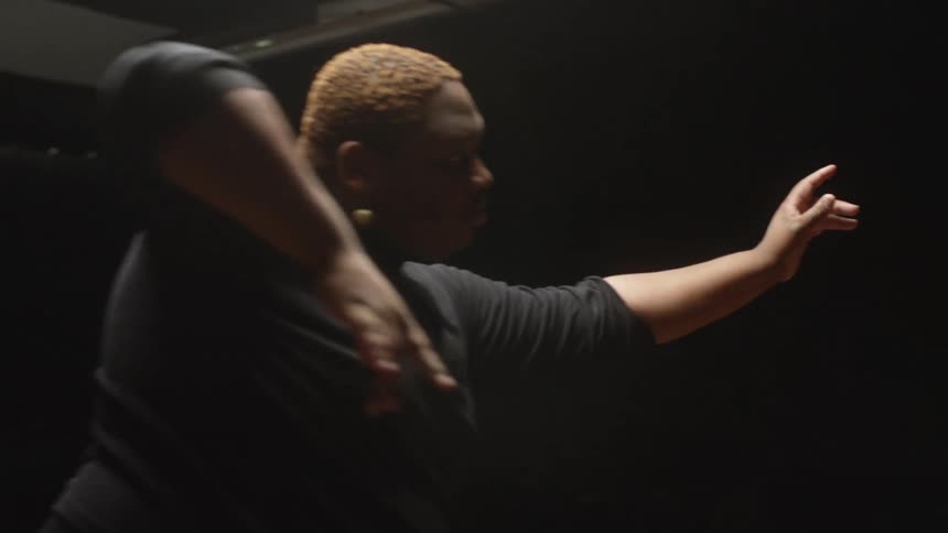 A man is dancing and performing under the light