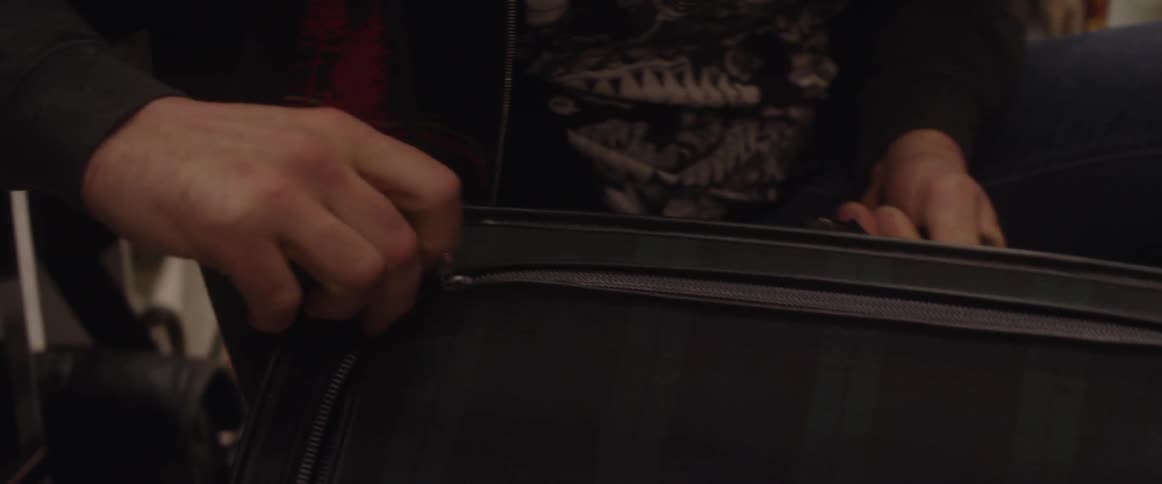 Man unzips and looks inside a small suitcase