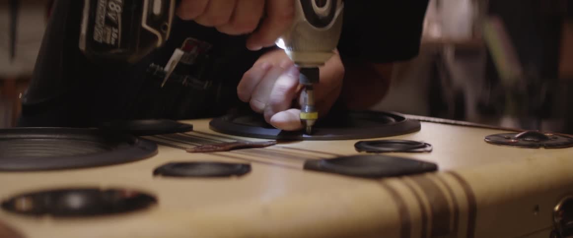 A man uses a drill to fix a speaker