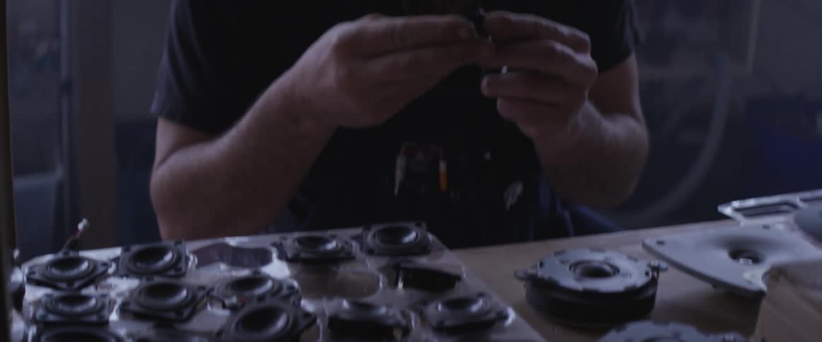 A man inspects speakers on a workshop table