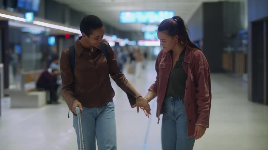 Two women hug then walk away hand in hand