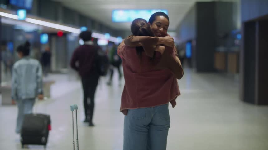 A woman is greeting with a hug in the terminal
