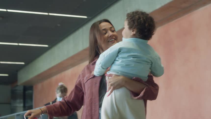 A woman comes up the escalator and is greeted by her family