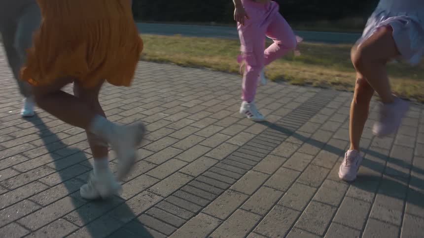 A group of young woman dance in formation on a walkway outdoors during the day