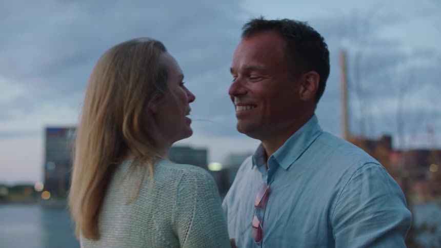 A man and woman hug by the water then walk away from eachother