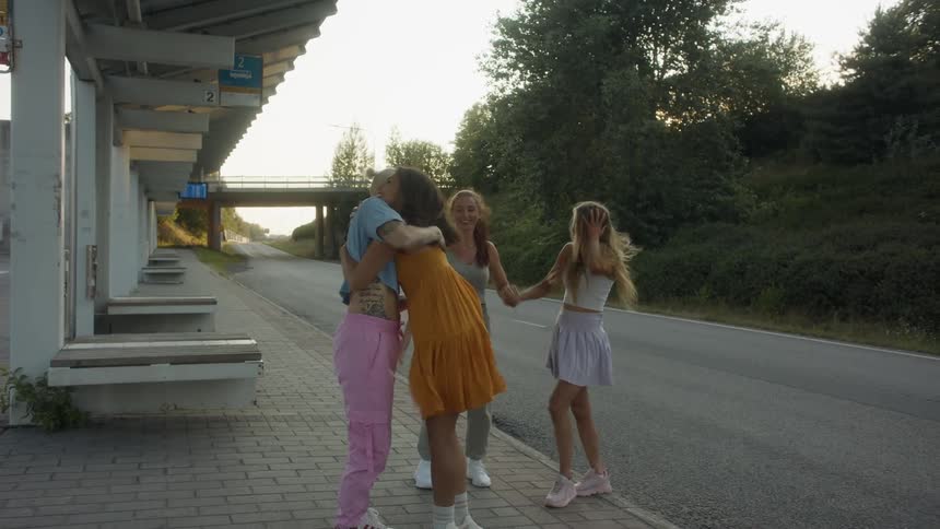 Young girls hug and greet each other on the street at sunset