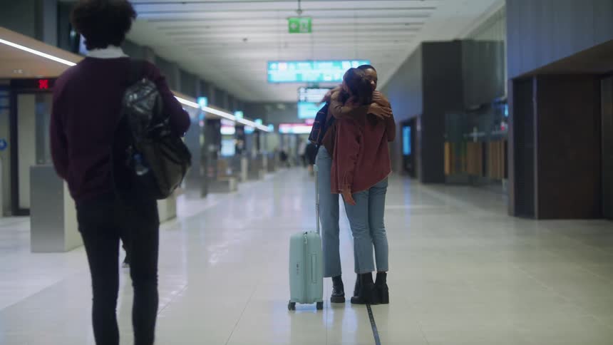 Two friends greet each other with a hug on the corridor of a passenger terminal
