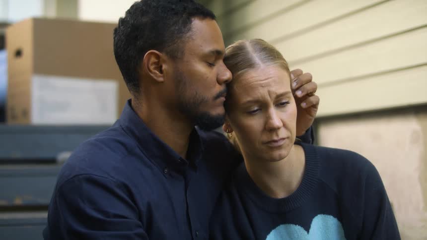 A man and woman hugging sad outdoors