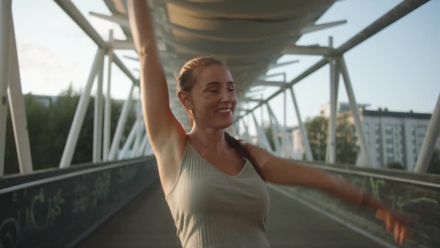 Young woman posing over a bridge near the city at sunset