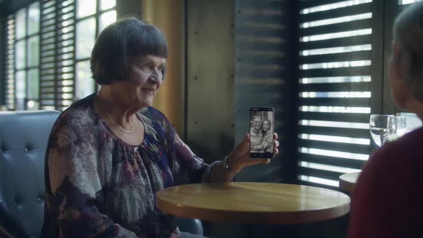 A woman shows a photo on her cellphone to a friend