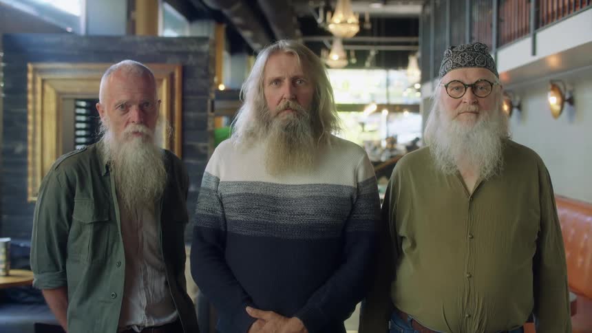 Three men pose side by side in the restaurant