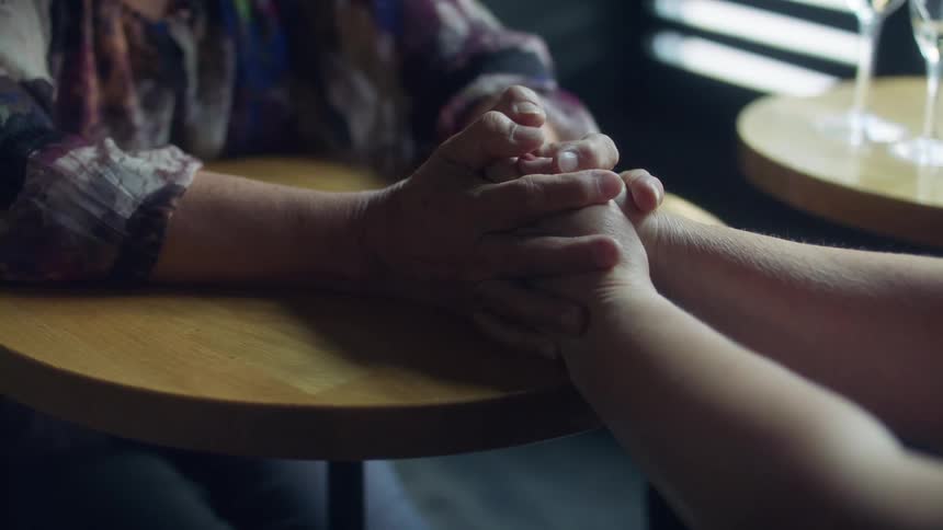 Two people hold hands in the bar