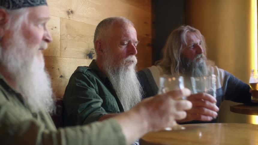 Three men toast and drink a beer together