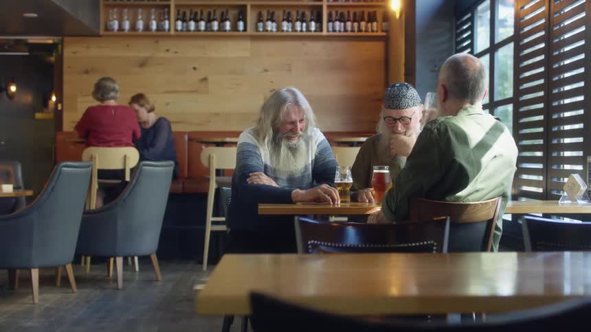 A waitress brings a beer over to a table of men having fun