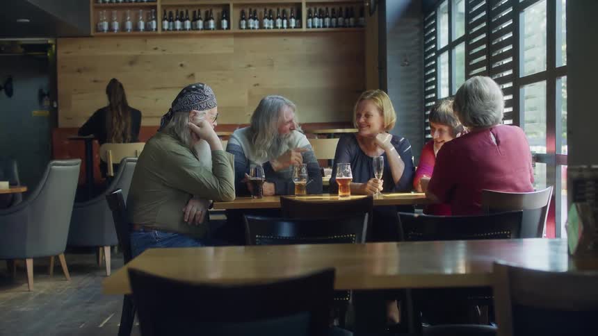Men and woman sitting at a table in a restaurant with a wall and window in the background