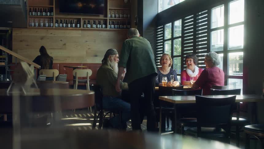 Group of elderly friends sitting at a table on a restaurant drinking beer