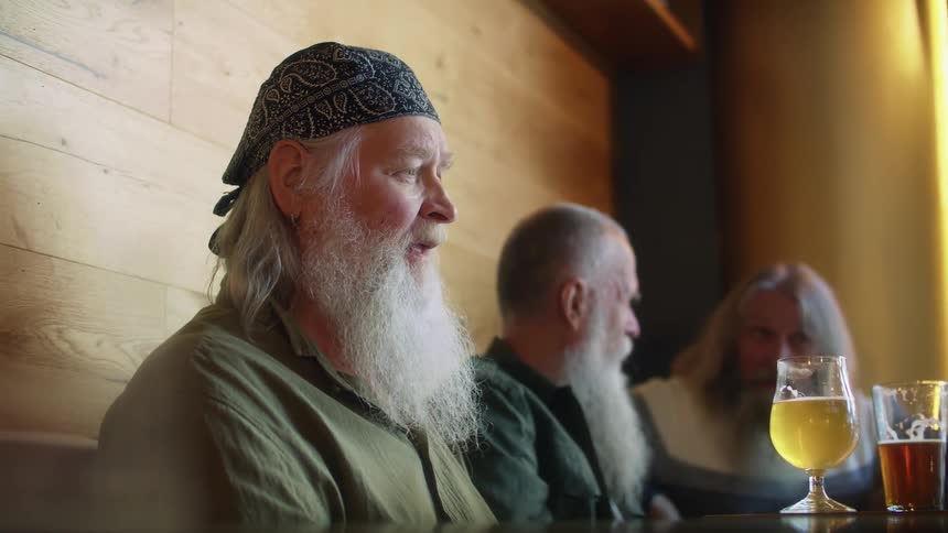 Group of bearded friends drinking beer in a bar
