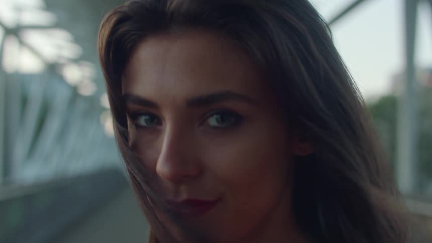 Woman with brown hair and make up faces the camera with eye contact smiling