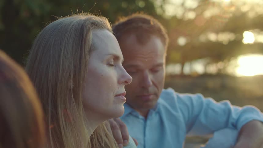 A family sits in a park with their eyes closed