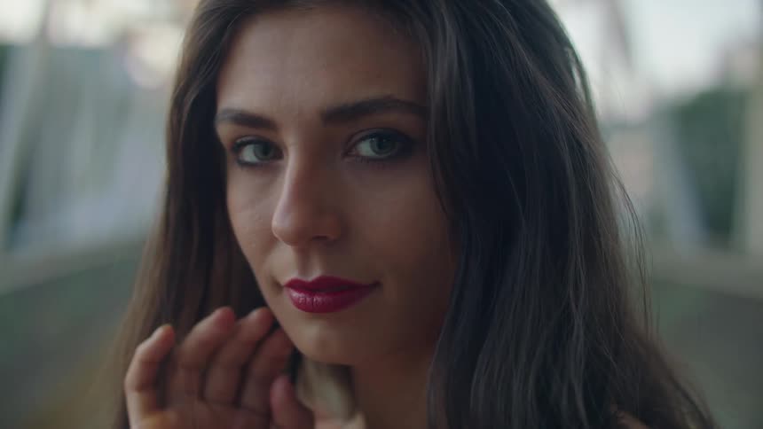 Woman with makeup and brown hair looks at the camera on the bridge