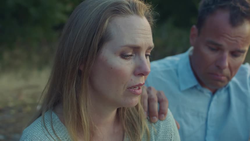 A man has his hand on the shoulder of a sad woman