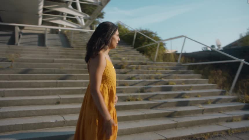 Group of friends wearing colorful clothes dancing near the stairs on the city at sunset