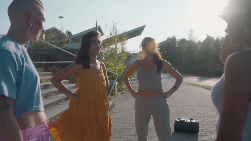 Group of young friends talking and laughing standing near a park at sunset