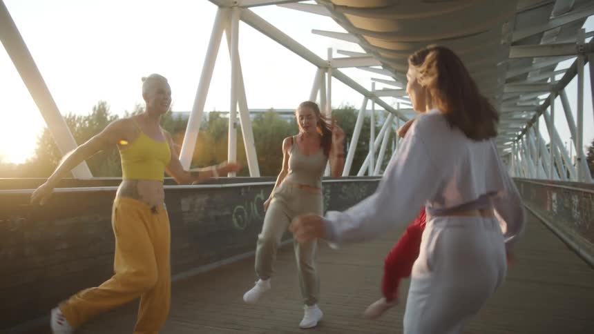 Four women are dancing together on the overpass