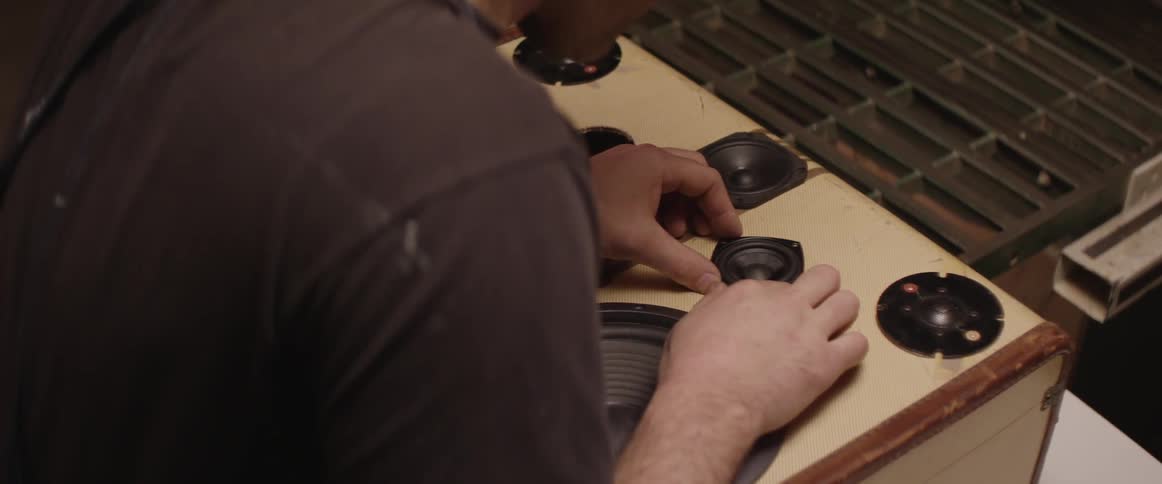 A man adjust tiny speakers on a suitcase