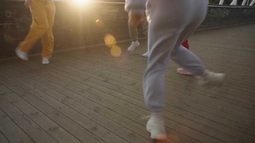 A group of four young women happily dance together while on a pedestrian bridge