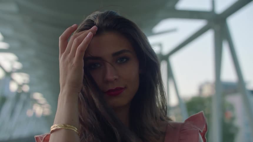 A woman is smiling as she brushes her hair back