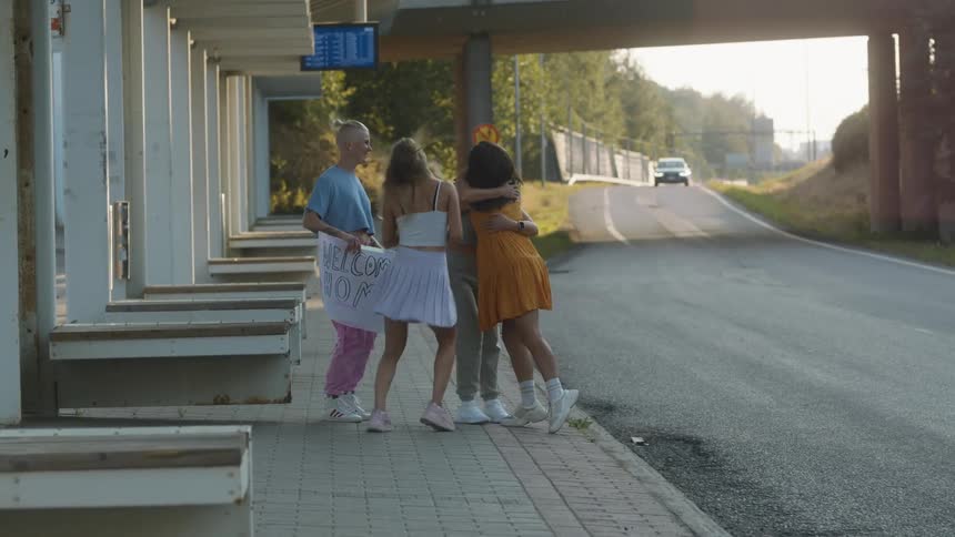 Three female friends welcome home another woman outdoors in the evening