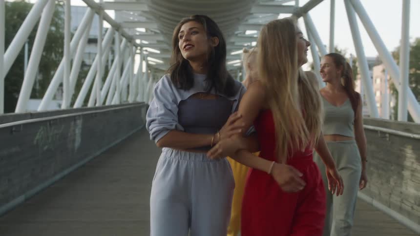 A group of female dancers walks on bridge chatting with each other