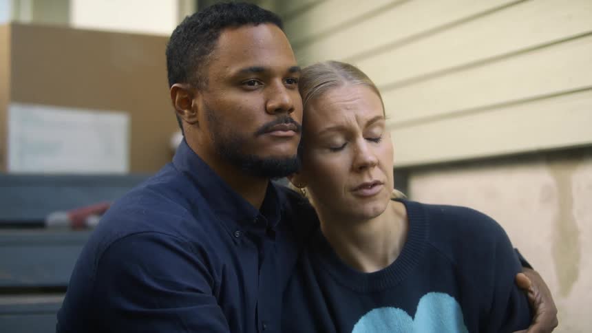 A man holds a woman close as he consoles her while shes clearly sad