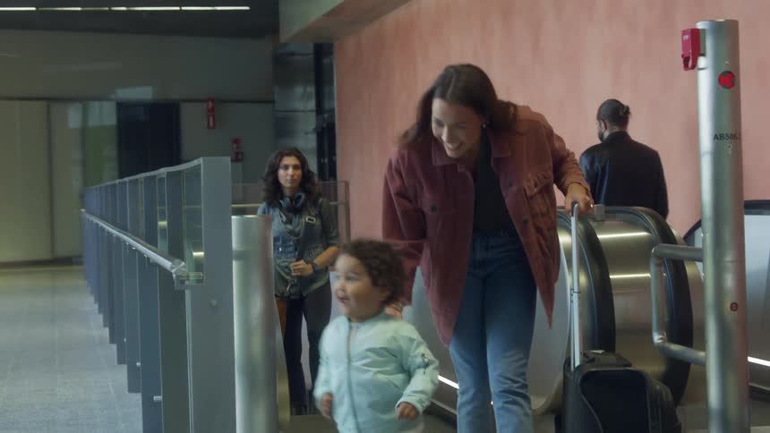 A woman comes up the escalators as kids and a man welcome her