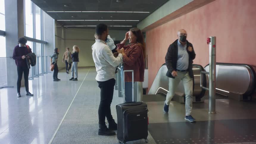 Father holding his sond on his arms greets his wife on a passenger terminal