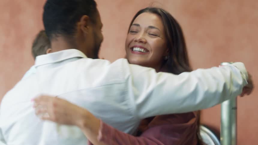 Woman hugs and picks up child before hugging man holding another child
