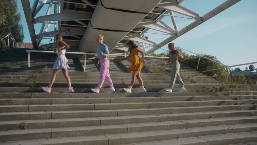 Four women dance on the steps under the overpass