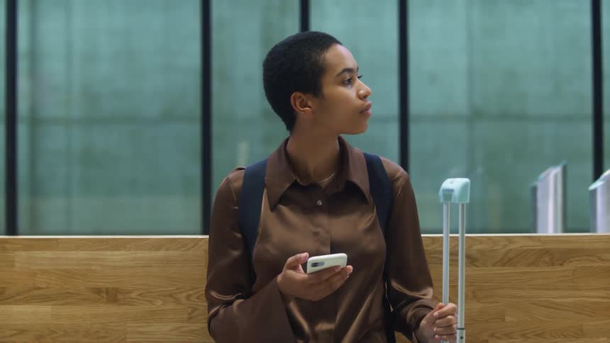 Young woman sitting at a passenger terminal checking her phone